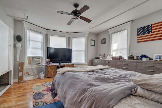 bedroom with ceiling fan, multiple windows, cooling unit, and light wood-style floors