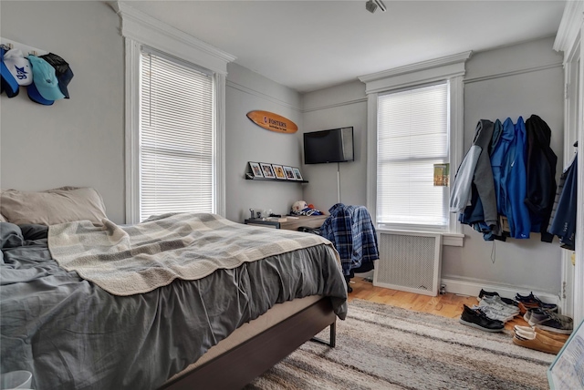 bedroom featuring baseboards, wood finished floors, and radiator