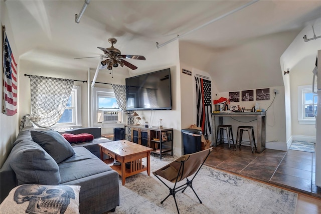 tiled living room featuring ceiling fan, baseboards, and cooling unit