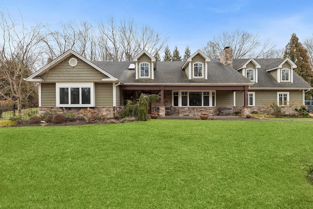 cape cod house featuring stone siding, a shingled roof, a chimney, and a front lawn