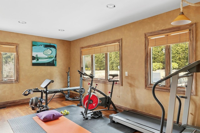 exercise room with baseboards, wood finished floors, and recessed lighting