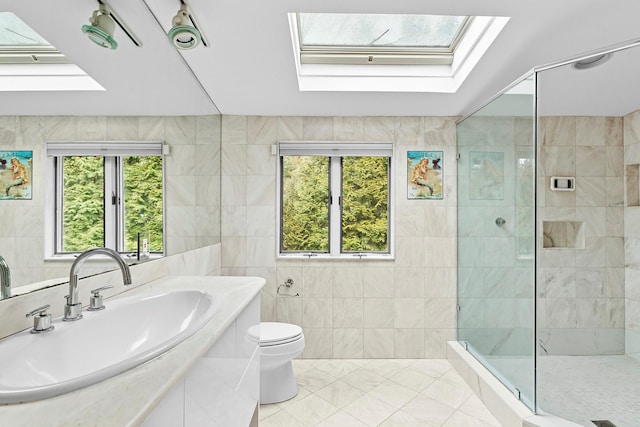 bathroom featuring toilet, a skylight, vanity, tile walls, and walk in shower