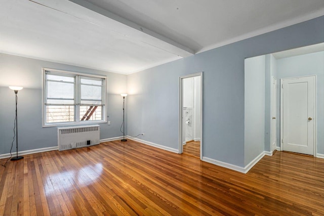 empty room featuring radiator, beamed ceiling, wood-type flooring, and baseboards