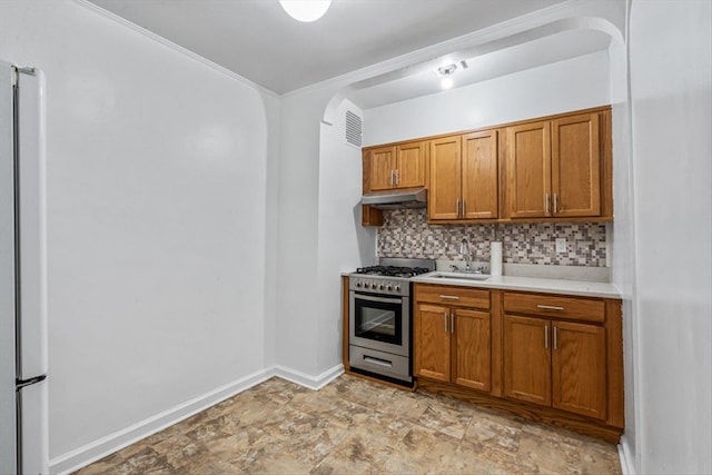 kitchen featuring a sink, light countertops, stainless steel gas range, backsplash, and brown cabinetry