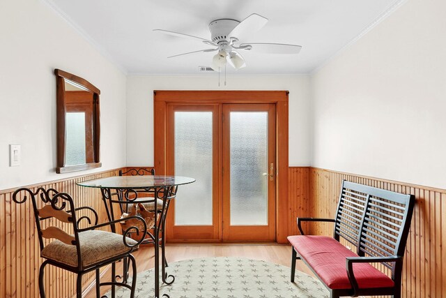 interior space with a wainscoted wall, ornamental molding, and wood finished floors