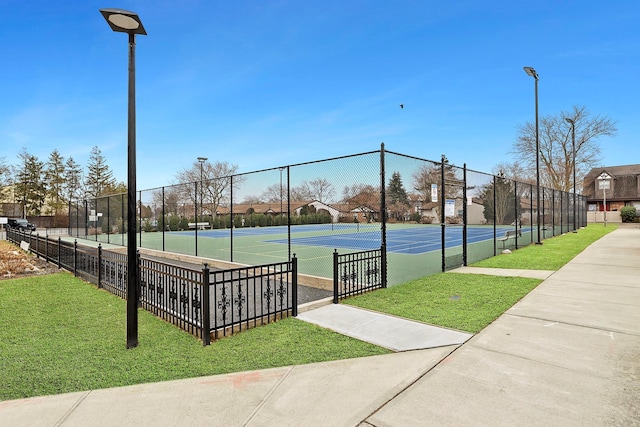 view of sport court with fence and a lawn