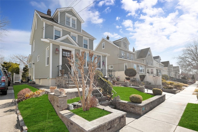 american foursquare style home with a residential view, a chimney, and a front yard