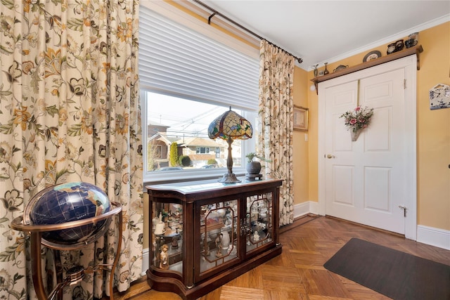 foyer entrance with crown molding and baseboards