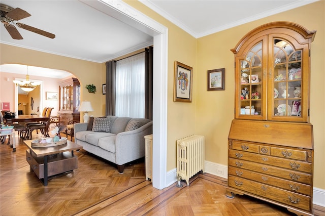 living area with arched walkways, ceiling fan with notable chandelier, baseboards, radiator, and crown molding