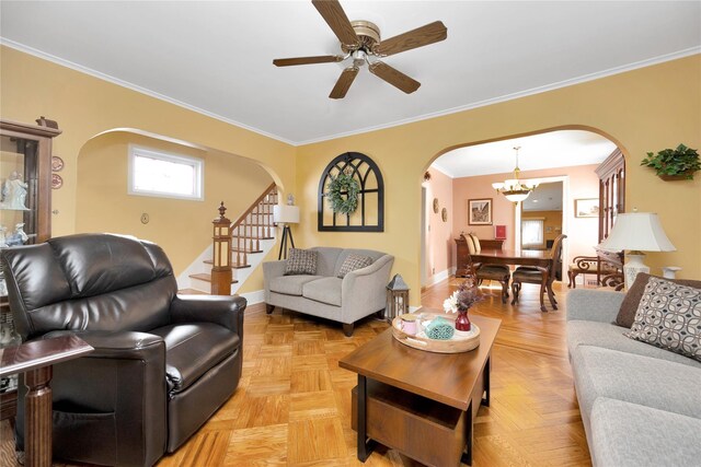 living area featuring stairs, arched walkways, ornamental molding, baseboards, and ceiling fan with notable chandelier