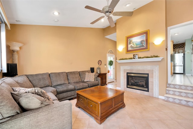 living room featuring a ceiling fan, a tiled fireplace, light tile patterned flooring, high vaulted ceiling, and recessed lighting