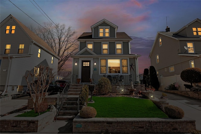 american foursquare style home featuring concrete driveway and a yard