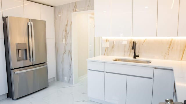 kitchen featuring a sink, marble finish floor, light countertops, stainless steel fridge with ice dispenser, and modern cabinets