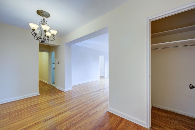 interior space featuring light wood-type flooring, an inviting chandelier, and baseboards