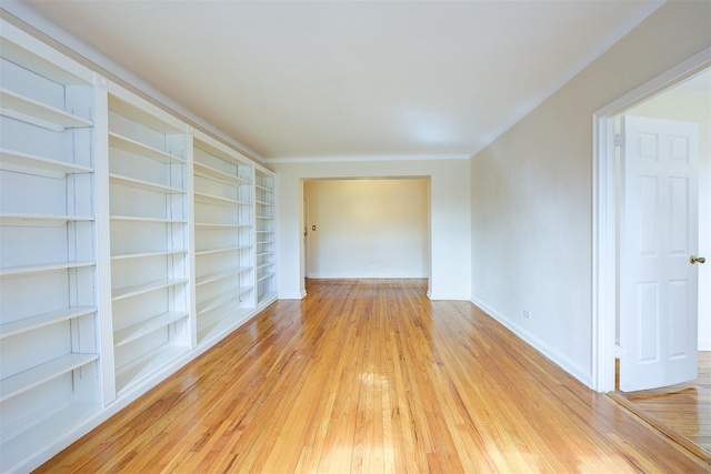 empty room with built in shelves, baseboards, and hardwood / wood-style floors