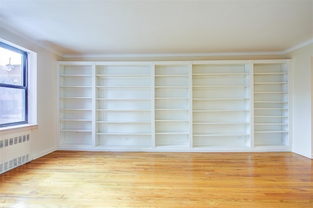 empty room featuring light wood-style floors and radiator heating unit