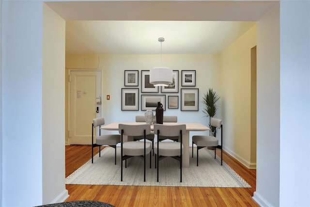 dining space with light wood-type flooring and baseboards