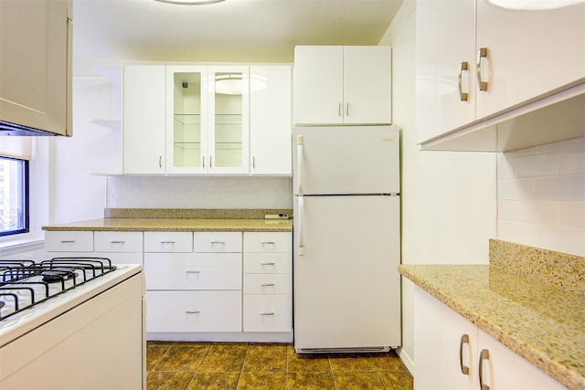 kitchen with tasteful backsplash, glass insert cabinets, freestanding refrigerator, and white cabinets