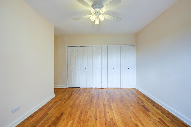 unfurnished bedroom featuring ceiling fan, light wood finished floors, two closets, and baseboards