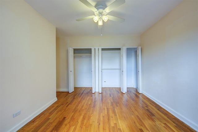 unfurnished bedroom featuring baseboards, ceiling fan, light wood finished floors, and multiple closets