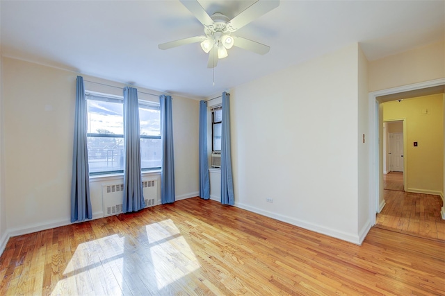 unfurnished room featuring baseboards, light wood-type flooring, a ceiling fan, and radiator