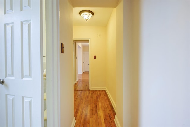 hallway with light wood-type flooring and baseboards