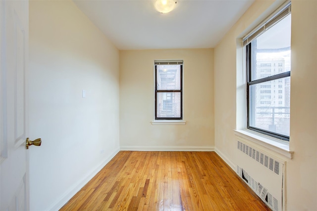 unfurnished room featuring baseboards, plenty of natural light, and radiator