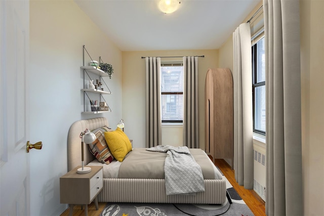 bedroom with light wood finished floors and radiator heating unit