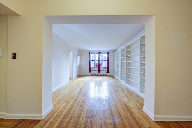 interior space with built in features, radiator heating unit, baseboards, and hardwood / wood-style floors