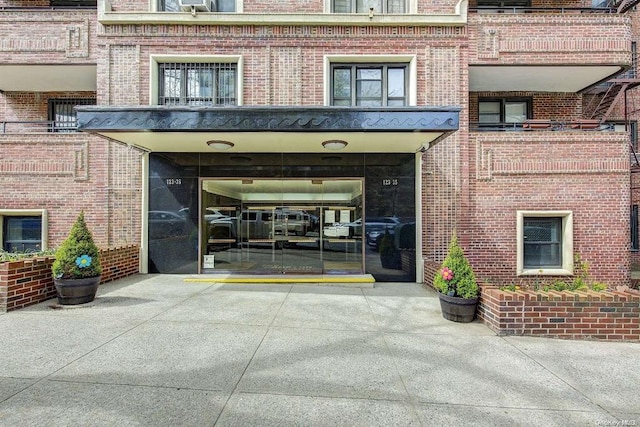 property entrance with driveway and brick siding