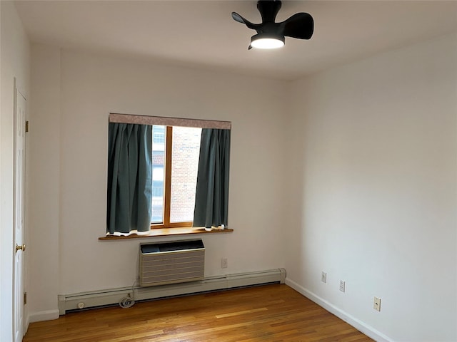 unfurnished room with baseboards, a ceiling fan, a wall unit AC, a baseboard radiator, and wood finished floors