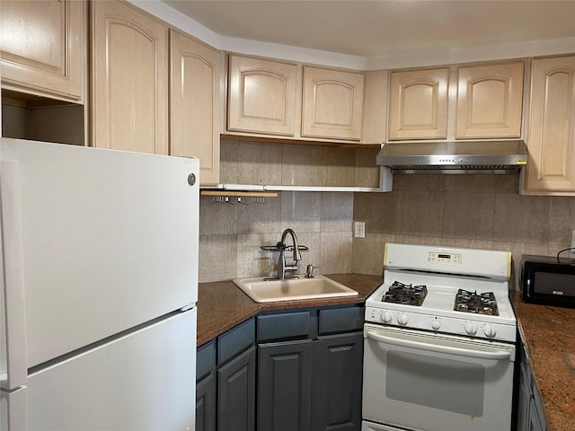 kitchen featuring white appliances, dark countertops, a sink, and under cabinet range hood