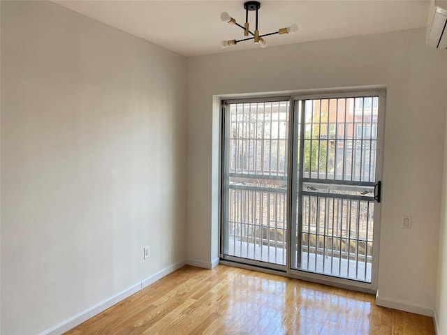 spare room featuring a wall unit AC, wood finished floors, and baseboards