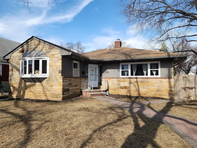 view of front of house featuring stone siding, a shingled roof, a chimney, and fence