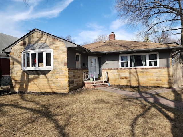 back of property with stone siding, a shingled roof, and a chimney