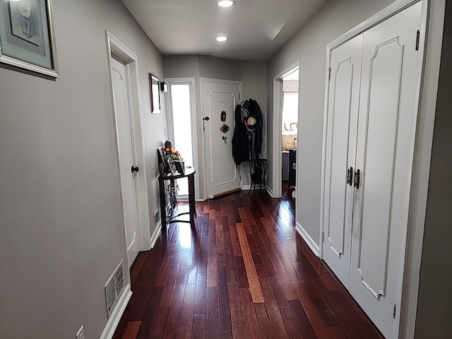 hall featuring baseboards, visible vents, dark wood-style flooring, and recessed lighting