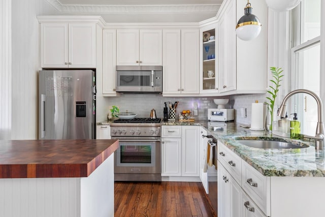 kitchen featuring white cabinets, butcher block counters, glass insert cabinets, stainless steel appliances, and a sink