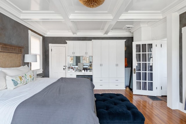 bedroom with beam ceiling, visible vents, built in study area, coffered ceiling, and hardwood / wood-style flooring