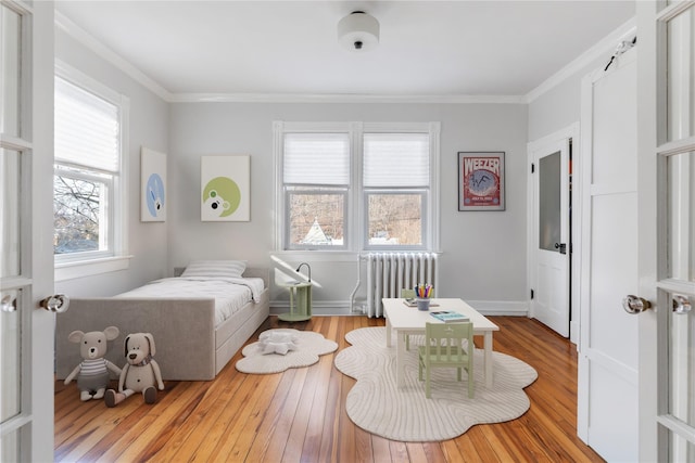 bedroom featuring ornamental molding, wood-type flooring, baseboards, and radiator heating unit