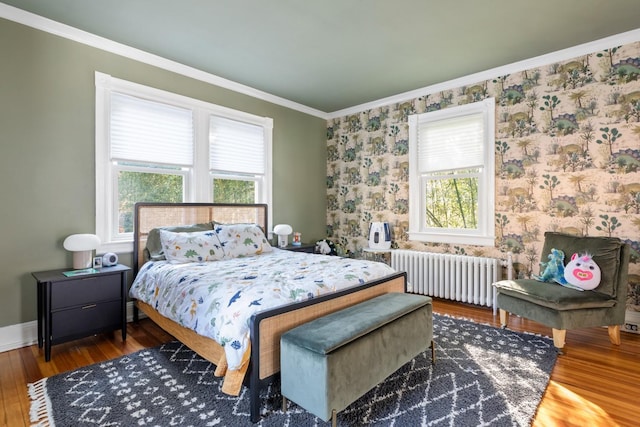 bedroom with ornamental molding, radiator, multiple windows, and wood finished floors