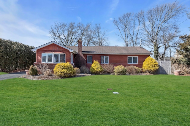 ranch-style house featuring driveway, a front lawn, a chimney, and fence