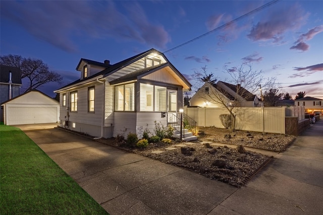 property exterior at dusk with a detached garage, fence, and an outbuilding