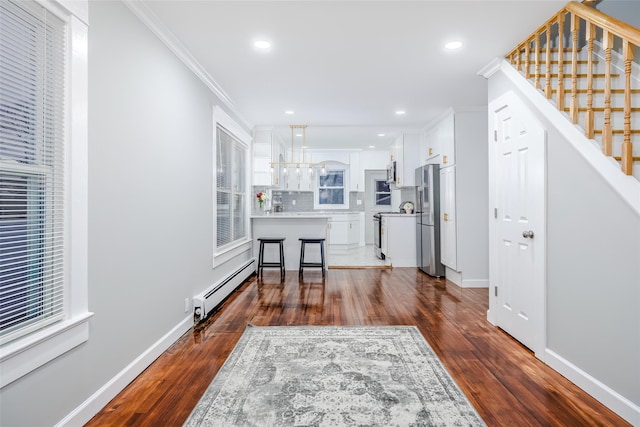 kitchen featuring a baseboard heating unit, white cabinets, appliances with stainless steel finishes, and dark wood-type flooring