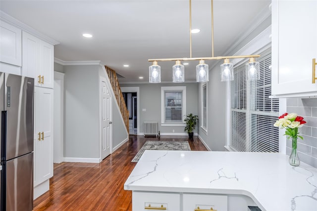 kitchen featuring white cabinets, ornamental molding, freestanding refrigerator, and light stone countertops