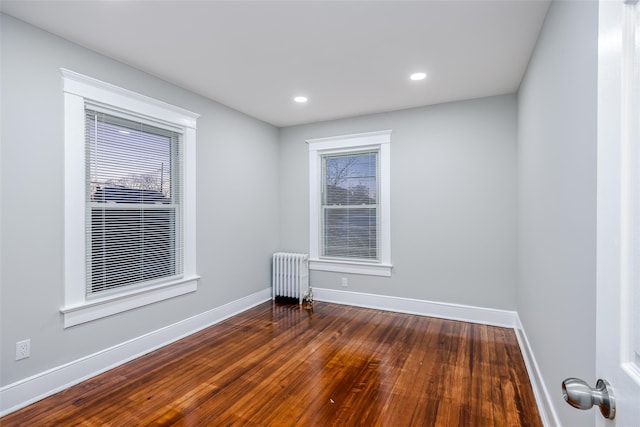 spare room with baseboards, dark wood-style flooring, recessed lighting, and radiator