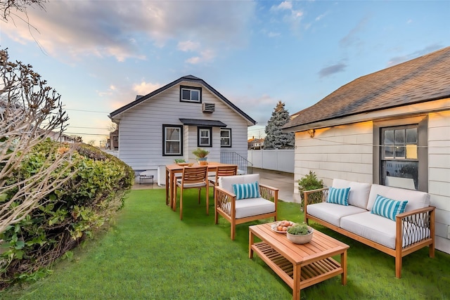 back of house at dusk with outdoor dining area, roof with shingles, a lawn, an outdoor hangout area, and a patio area