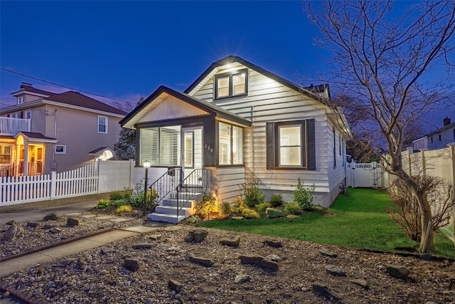 bungalow-style home featuring a front yard, a fenced backyard, and a gate