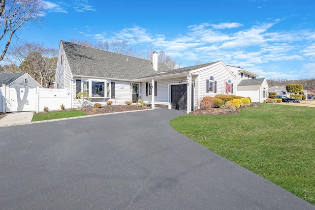 view of front of house with aphalt driveway, a chimney, an attached garage, a front yard, and fence