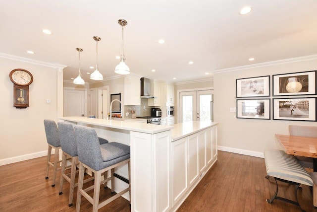 kitchen featuring decorative backsplash, wood finished floors, french doors, wall chimney range hood, and white cabinetry