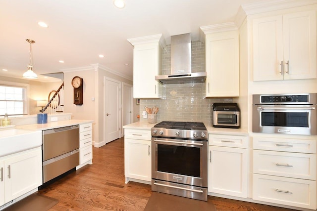 kitchen with crown molding, light countertops, backsplash, appliances with stainless steel finishes, and wall chimney exhaust hood